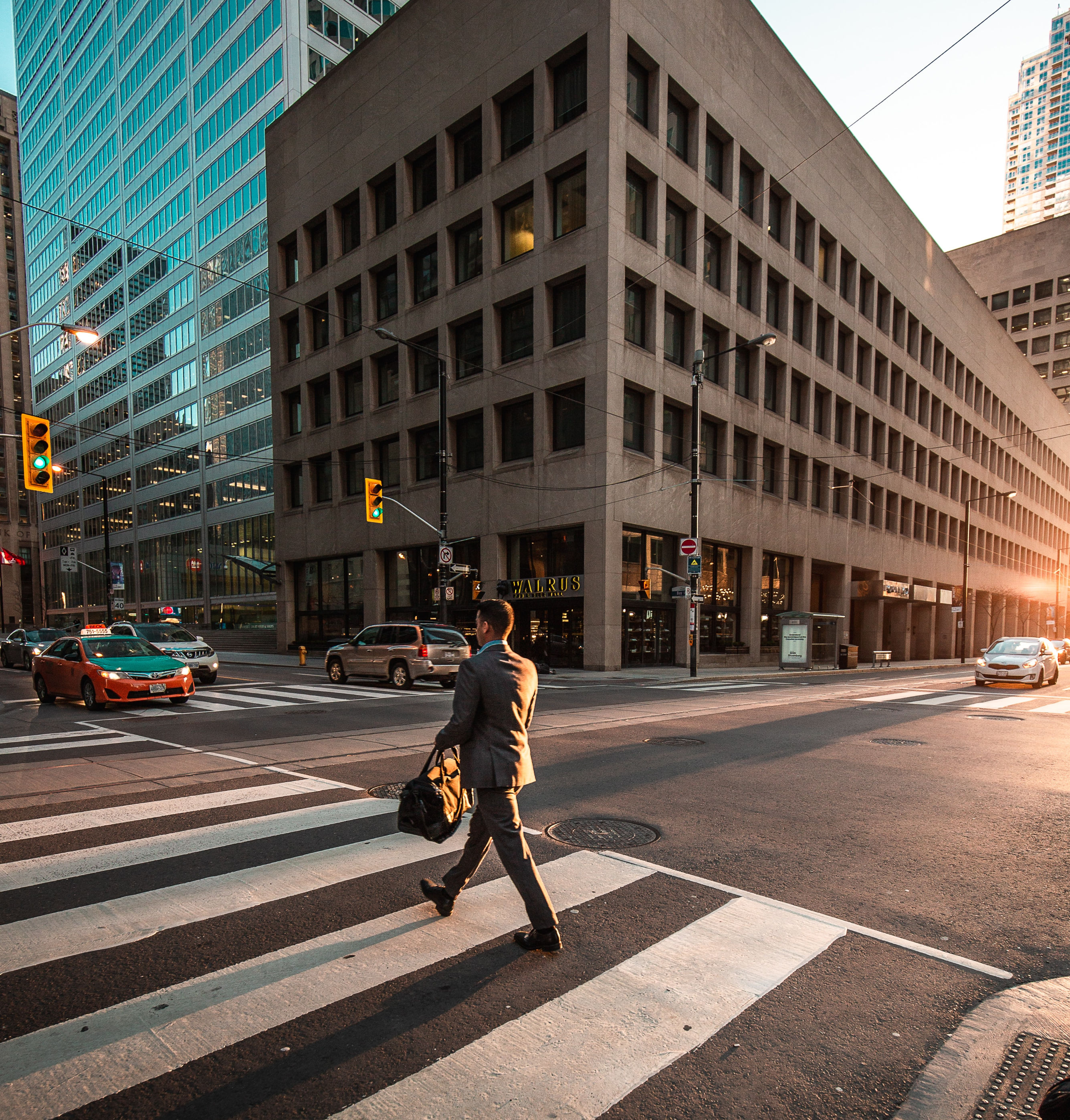 Man in suit walking across a city street. 